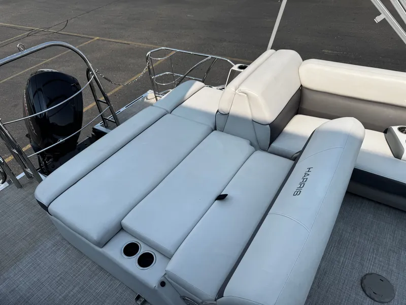 Slide: The Image of The image shows the rear of a 2021 Harris Cruiser 230 pontoon boat with cushioned seating and an outboard motor. - 21