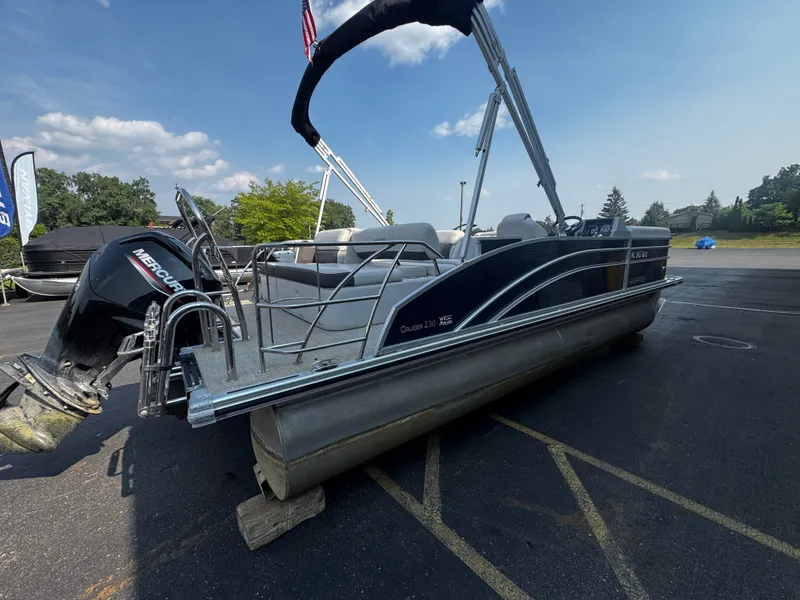 Slide: The Image of A 2021 Harris Cruiser 230 pontoon boat is parked on a lot. It features a Mercury outboard motor. - 2