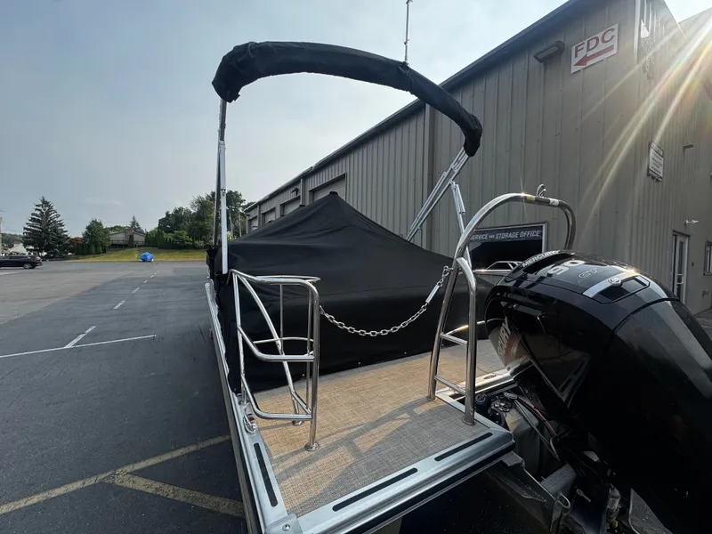 Slide: The Image of A 2021 Harris Cruiser 230 with a black cover, parked next to a building. - 29