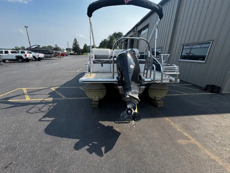 Slide: The Image of A 2021 Harris Cruiser 230 pontoon boat is parked on a lot. It features an outboard motor. - 8