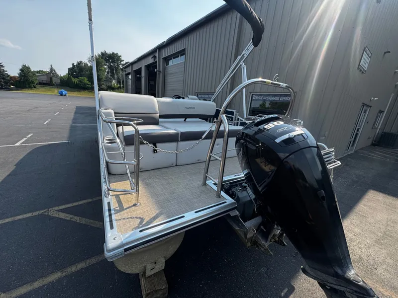 Slide: The Image of A 2021 Harris Cruiser 230 pontoon boat is parked on a lot. It features an outboard motor. - 7