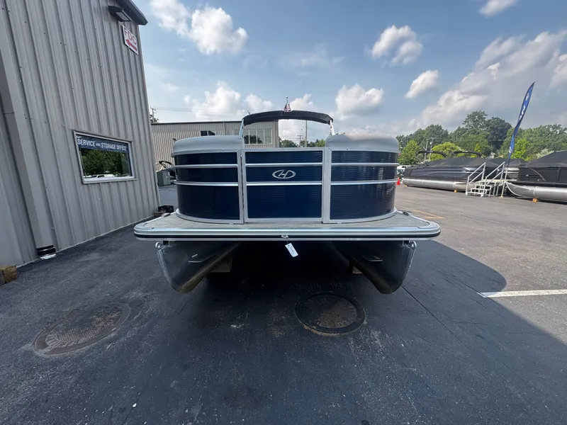 Slide: The Image of A 2021 Harris Cruiser 230 pontoon boat is parked on a lot in front of a building. - 3