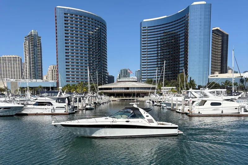 Slide: The Image of 1997 Sea Ray 370 Express Cruiser docked in a marina with modern buildings in the background. - 29