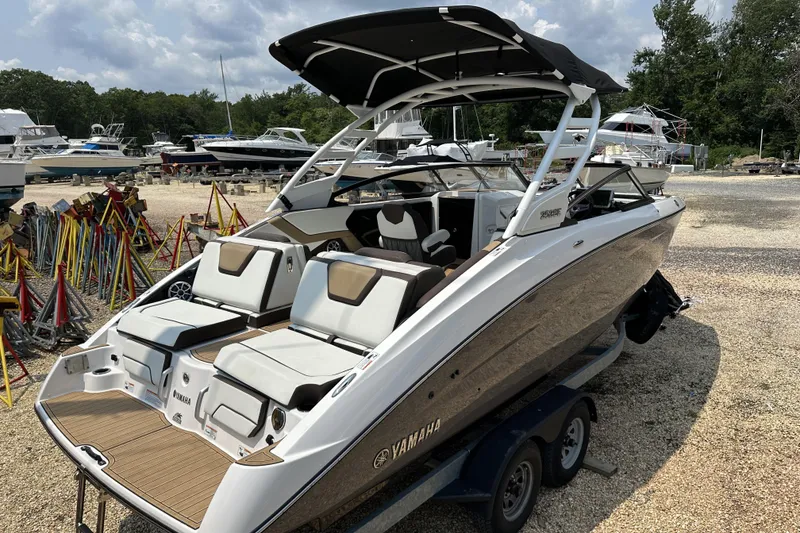 Slide: The Image of 2023 Yamaha Boats 252SE on trailer, sleek design, outdoor setting, multiple boats in background. - 12