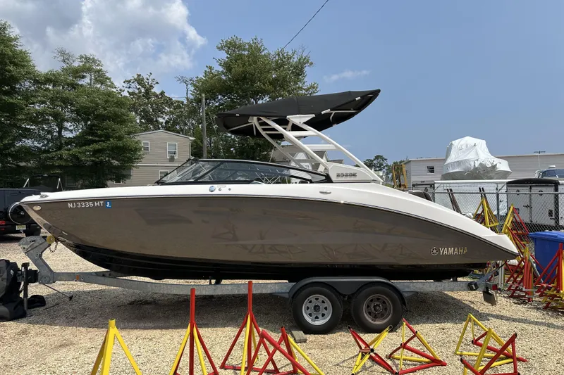 Slide: The Image of 2023 Yamaha Boats 252SE on trailer, parked outdoors with trees and buildings in background. - 3