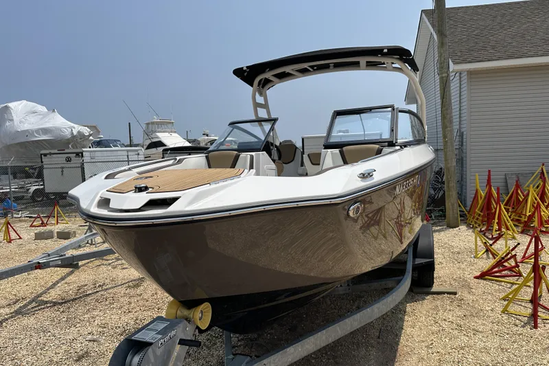 Slide: The Image of 2023 Yamaha Boats 252SE on trailer, displayed outdoors near other boats. - 18