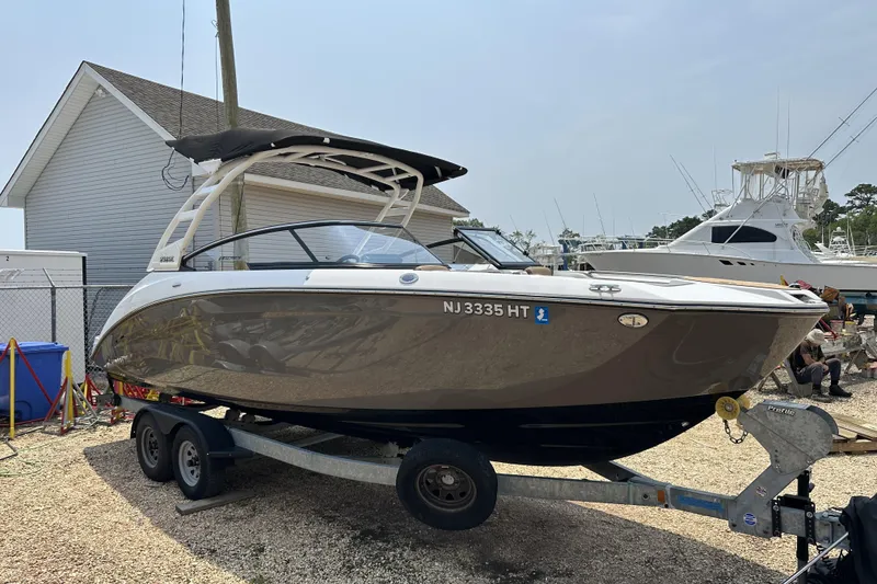 The Image of 2023 Yamaha Boats 252SE on trailer, parked outdoors near other boats. - 0