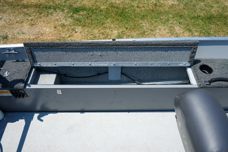 Slide: The Image of 2015 Lund 1400 Fury SS boat interior storage compartment with open lid, showing carpeted finish. - 6