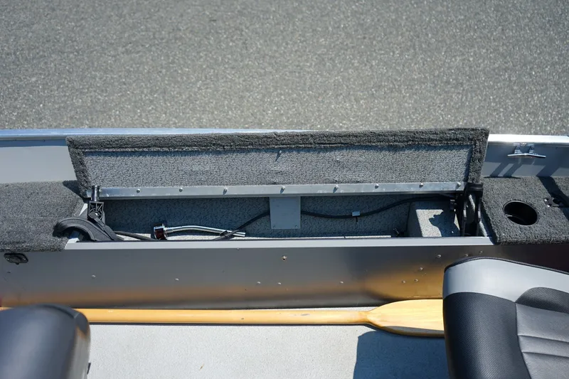 Slide: The Image of 2015 Lund 1400 Fury SS boat interior storage compartment with open lid and visible paddle. - 7