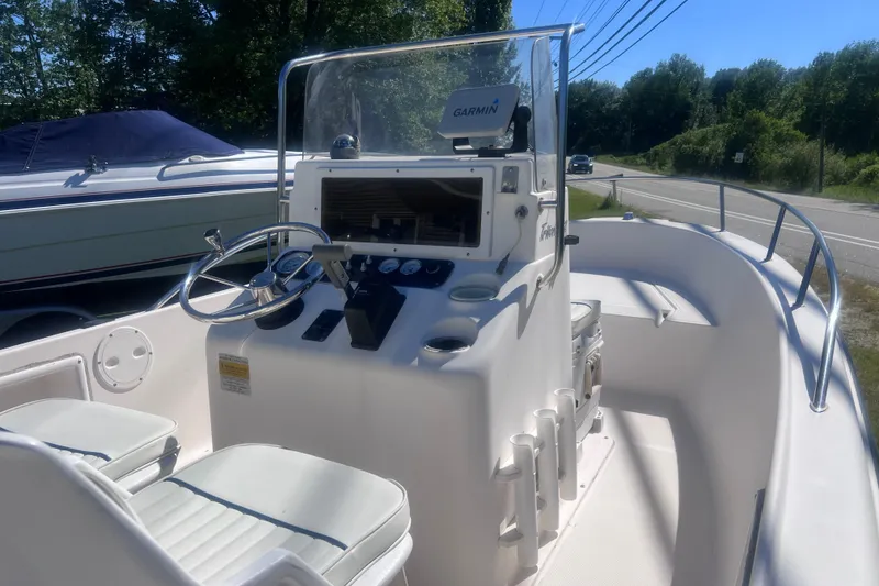 Slide: The Image of 2004 Sea Hunt Triton 177 boat interior with steering console and seating, parked near a road. - 9