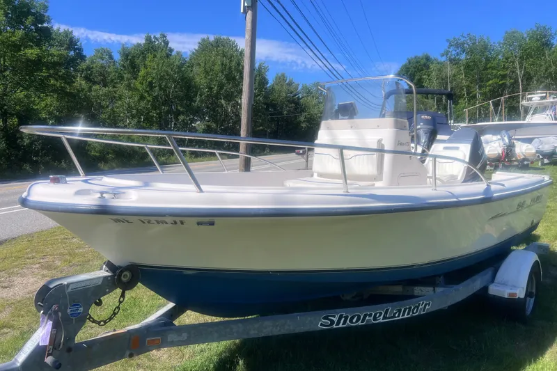 The Image of 2004 Sea Hunt Triton 177 boat on trailer, parked roadside with trees in background. - 1