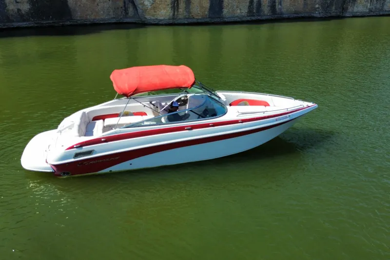 Slide: The Image of 2016 Crownline 275 SS boat with red canopy on calm green water. - 17