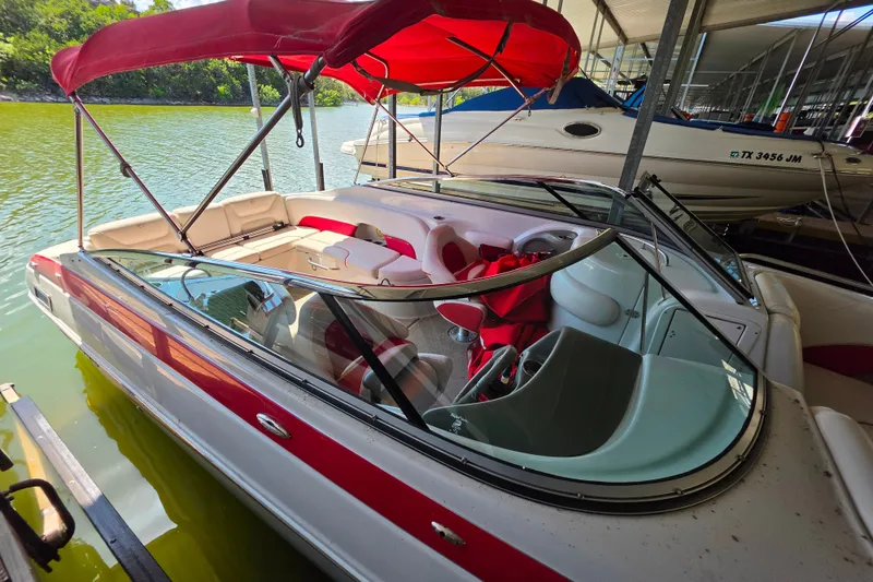 Slide: The Image of 2016 Crownline 275 SS boat with red canopy docked on a sunny day. - 15