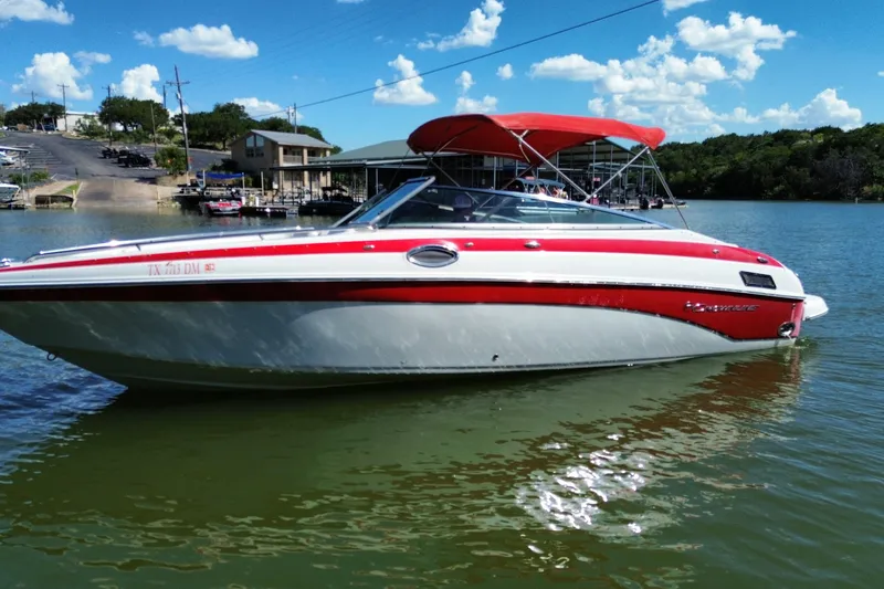 Slide: The Image of 2016 Crownline 275 SS boat with red accents on a sunny lake. - 11