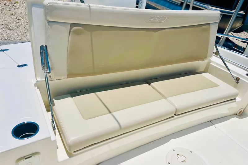 Slide: The Image of 2018 Boston Whaler 240 Dauntless boat seating area with beige cushions and cup holder. - 13