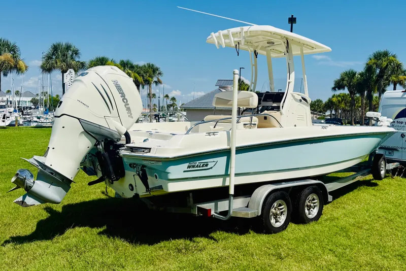 Slide: The Image of 2018 Boston Whaler 240 Dauntless boat on trailer, parked on grass with palm trees. - 6