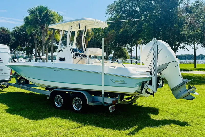 Slide: The Image of 2018 Boston Whaler 240 Dauntless boat on trailer, parked on grass with trees in background. - 4
