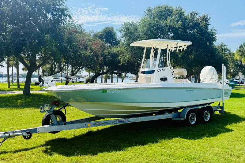 Slide: The Image of 2018 Boston Whaler 240 Dauntless boat on trailer, parked on grassy area near trees. - 2