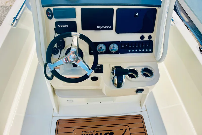 Slide: The Image of 2018 Boston Whaler 240 Dauntless helm with steering wheel, Raymarine electronics, and control panel. - 18