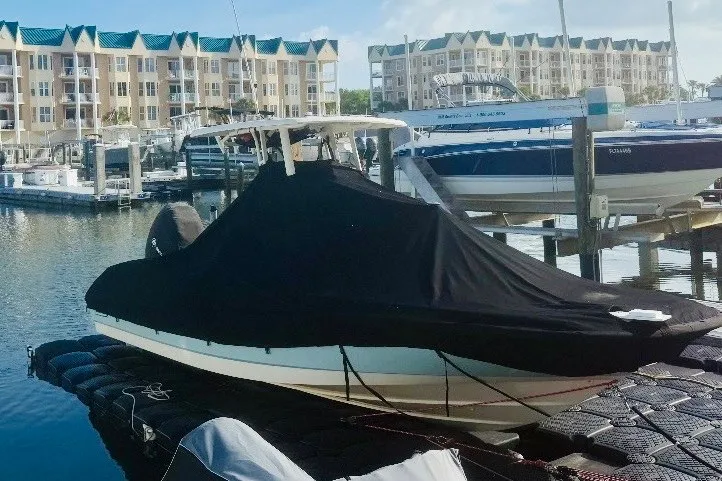 Slide: The Image of 2018 Boston Whaler 240 Dauntless covered at marina, with waterfront buildings in background. - 26