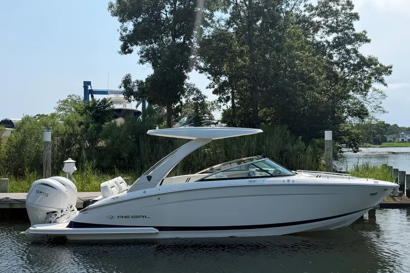 The Image of 2027 Regal LX9 boat docked by lush greenery and calm waters. - 0