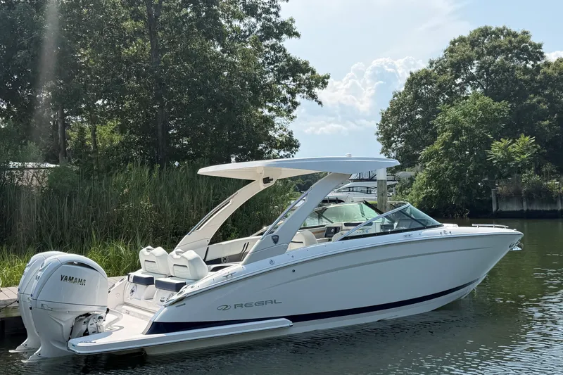 Slide: The Image of 2027 Regal LX9 boat with Yamaha engine docked on a serene river, surrounded by lush greenery. - 2