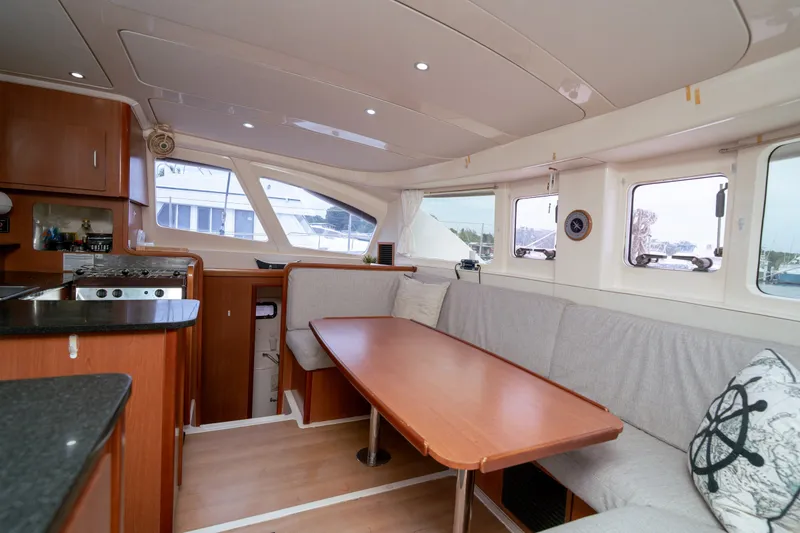 Slide: The Image of Interior of 2011 Leopard 38 catamaran with dining area and kitchen, featuring wood finishes. - 113