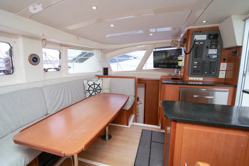 Slide: The Image of Interior of a 2011 Leopard 38 catamaran featuring a cozy dining area and navigation panel. - 103