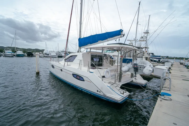Slide: The Image of 2011 Leopard 38 catamaran docked at marina, featuring blue sail and spacious deck. - 12