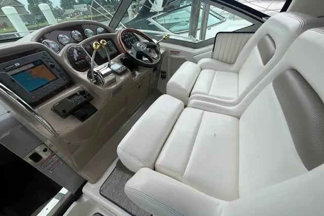 Slide: The Image of 2004 Sea Ray Sundancer 320 cockpit with dual white leather seats and navigation controls. - 13