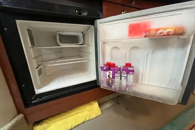Slide: The Image of Open mini fridge on a 2004 Sea Ray Sundancer 320 boat, containing drinks and a towel nearby. - 27
