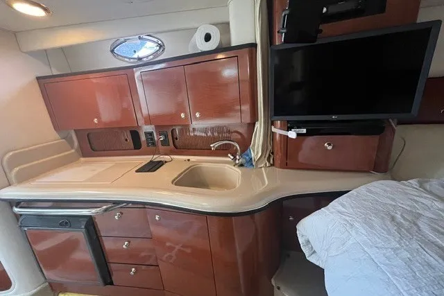Slide: The Image of 2004 Sea Ray Sundancer 320 interior with kitchenette, sink, cabinets, and mounted TV. - 22
