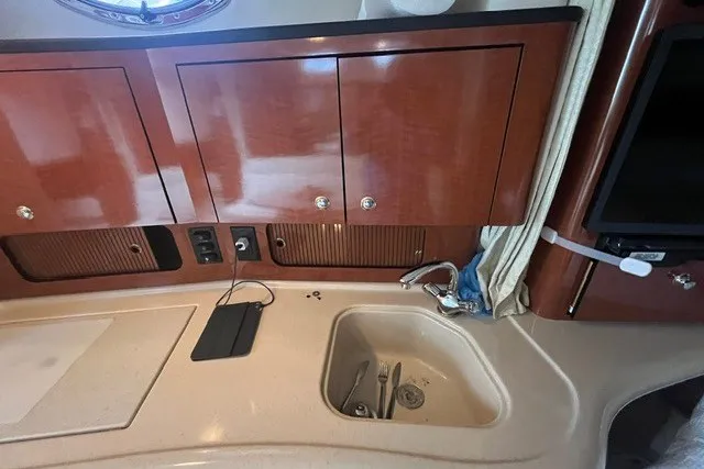 Slide: The Image of 2004 Sea Ray Sundancer 320 interior with wooden cabinets and compact sink area. - 23