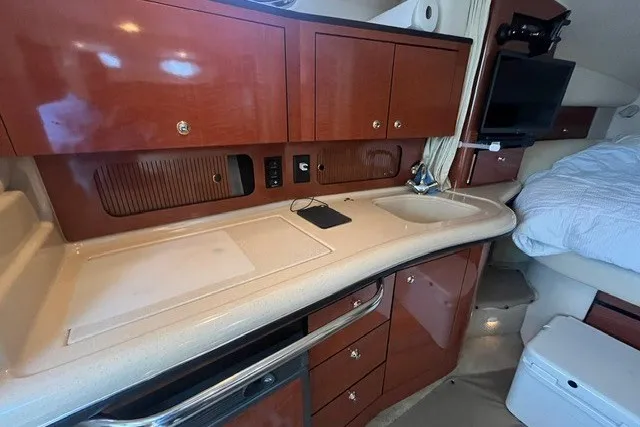 Slide: The Image of 2004 Sea Ray Sundancer 320 interior with wooden cabinetry, countertop, and cozy sleeping area. - 21