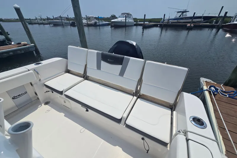 Slide: The Image of 2022 Robalo R230 Center Console boat with white seating at a marina dock. - 13