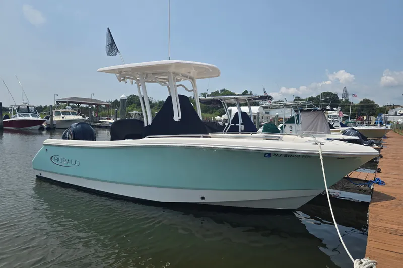 Slide: The Image of 2022 Robalo R230 Center Console boat docked in a marina under clear skies. - 2