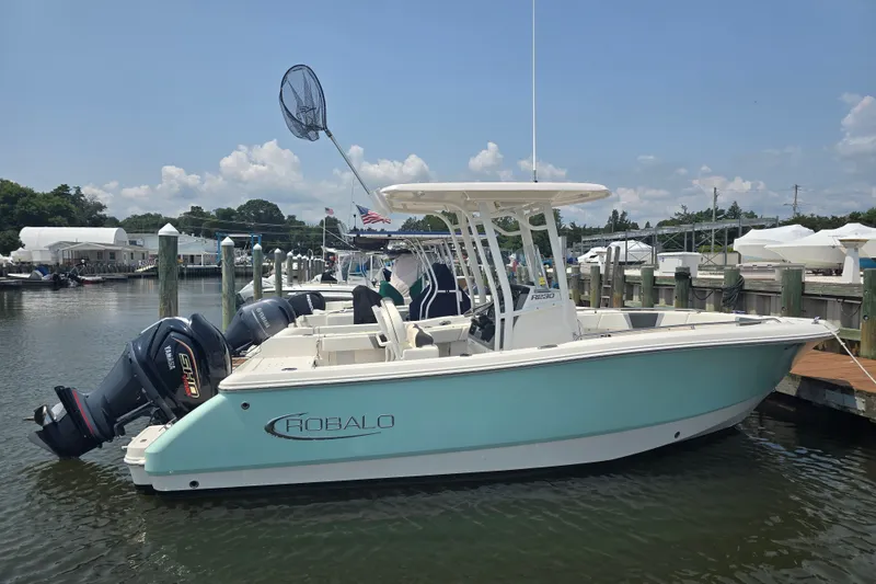 Slide: The Image of 2022 Robalo R230 Center Console boat docked in marina, featuring dual Yamaha engines. - 1