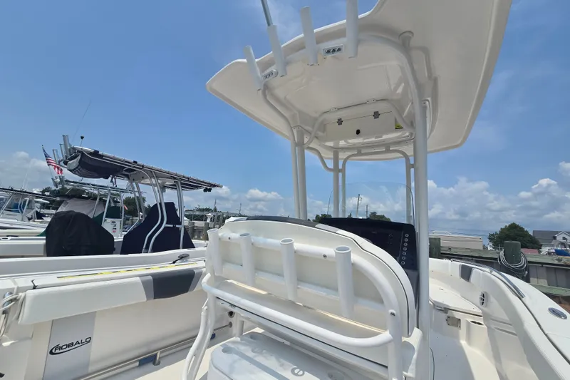 Slide: The Image of 2022 Robalo R230 Center Console boat with T-top and rod holders, docked under clear skies. - 14