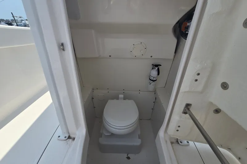 Slide: The Image of 2022 Robalo R230 Center Console boat interior with compact marine toilet and fire extinguisher. - 17