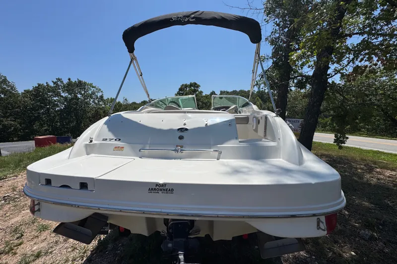 Slide: The Image of 2003 Searay 270 Sundeck boat with canopy, parked outdoors near trees and road. - 6