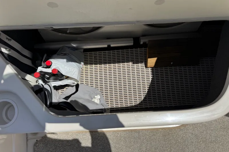 Slide: The Image of Storage compartment in a 2003 Searay 270 Sundeck boat with bags and bottles. - 32