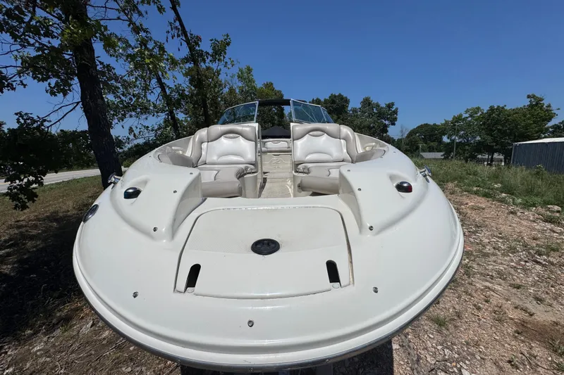 Slide: The Image of 2003 Searay 270 Sundeck boat on land, surrounded by trees under clear blue sky. - 7