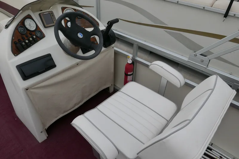 Slide: The Image of Steering console of a 2002 Avalon Tahoe Vista boat with white seating and controls. - 9