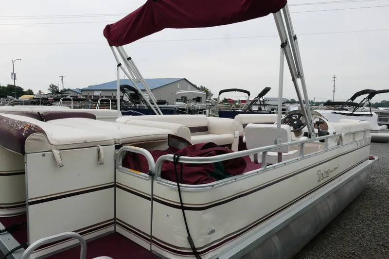 Slide: The Image of 2002 Avalon Tahoe Vista pontoon boat with maroon canopy and white seating, docked outdoors. - 3