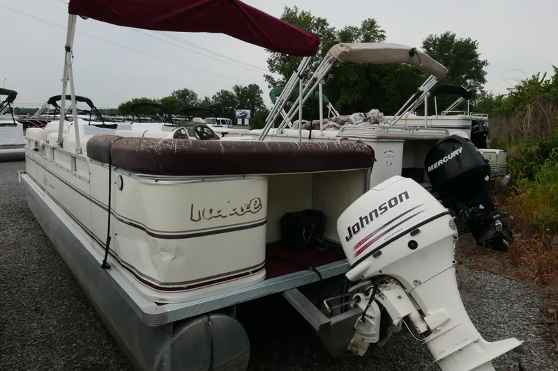 Slide: The Image of 2002 Avalon Tahoe Vista pontoon boat with Johnson outboard motor, parked on gravel. - 2