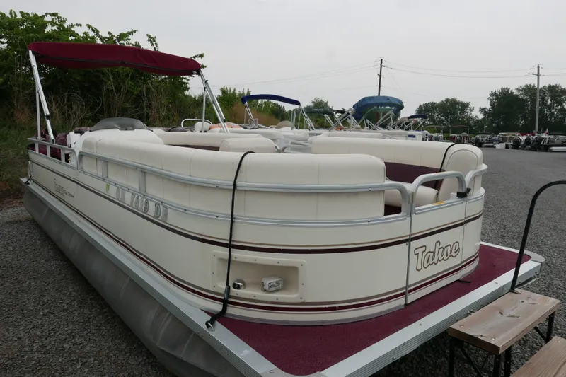 The Image of 2002 Avalon Tahoe Vista pontoon boat with maroon accents, parked on gravel. - 0