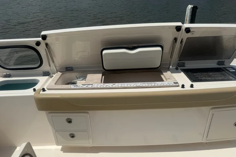 Slide: The Image of 2017 Pursuit S 408 Sport boat with open storage compartments and sink, docked by the water. - 28