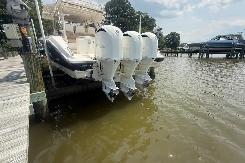 Slide: The Image of 2017 Pursuit S 408 Sport boat with triple Yamaha outboard engines docked by the water. - 62