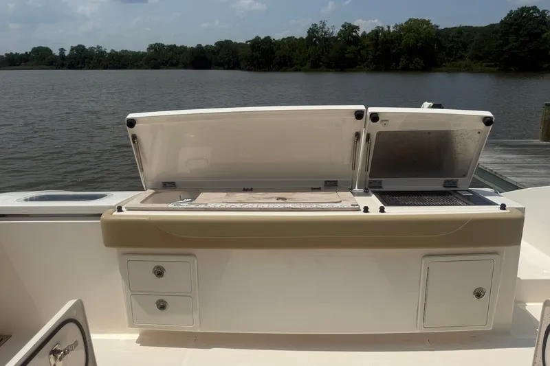 Slide: The Image of 2017 Pursuit S 408 Sport boat with open storage compartments by a lake. - 25