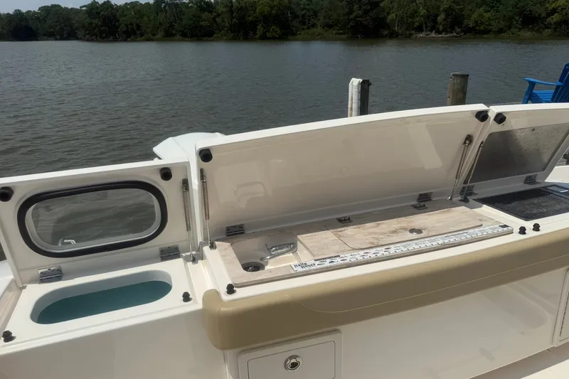 Slide: The Image of 2017 Pursuit S 408 Sport boat with open storage compartments by the water. - 26